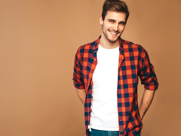 Портрет красивые улыбающиеся стильный молодой человек модель, одетый в красной клетчатой рубашке Модный мужчина позирует