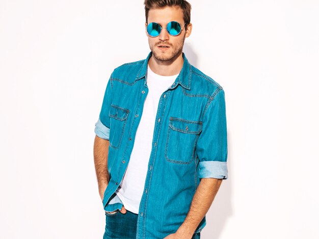 Portrait of handsome smiling stylish young man model wearing jeans clothes and sunglasses. Fashion man 