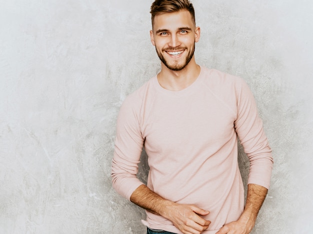 Foto gratuita ritratto del modello sorridente bello del giovane che indossa i vestiti casuali di rosa di estate. posa alla moda dell'uomo di modo