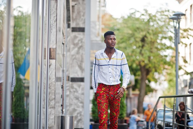 Portrait of handsome stylish african american model man in red throusers and white shirt