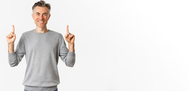 Foto gratuita ritratto di un bel uomo di successo con i capelli corti e grigi che sorride soddisfatto e indica le dita.