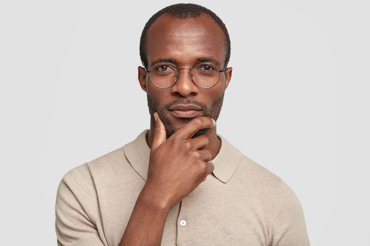 Free Photo portrait of handsome unshaven dark skinned male holds chin