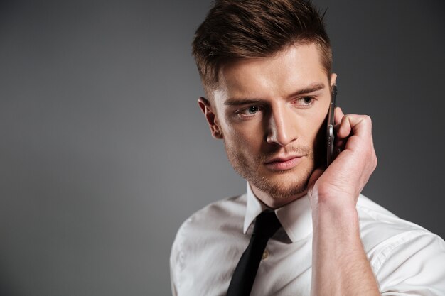 Портрет красивый молодой бизнесмен разговаривает по мобильному телефону