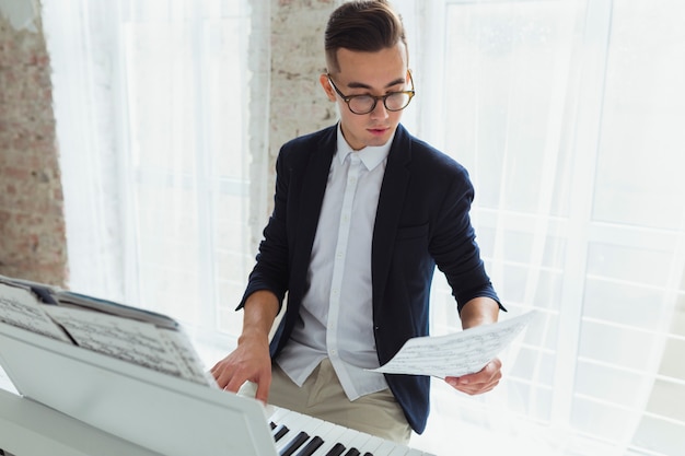 Portrait of a handsome young man looking at musical sheet playing piano
