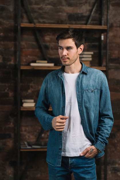 Portrait of handsome young man standing in from of bookshelf