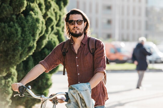 Portrait of a handsome young man walking with bicycle on the road