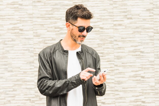 Portrait of handsome young man wearing sunglasses using smartphone