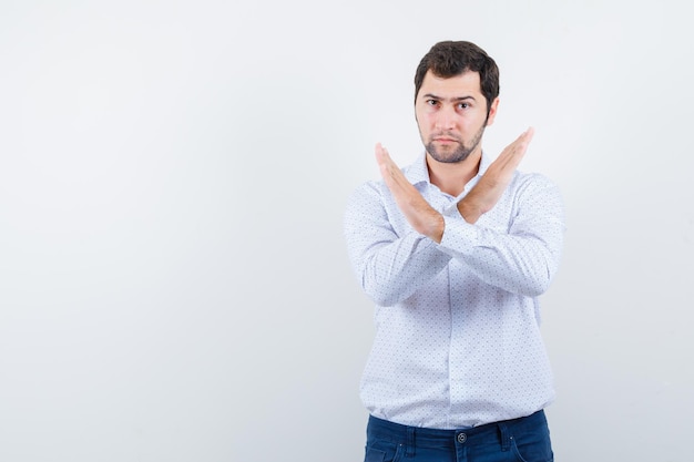 Free photo portrait of handsome young man in white patterned shirt crossed arms and looking so serious isolated on white background