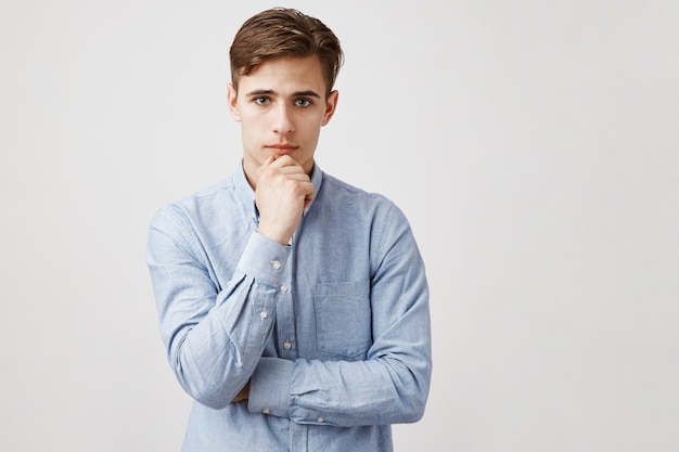 Portrait of handsome young man with hand on chin, thoughtful look