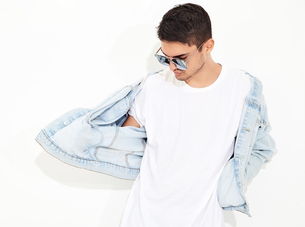 Portrait of handsome young model man dressed in jeans clothes in sunglasses posing. Isolated