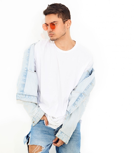 Portrait of handsome young model man dressed in jeans clothes in sunglasses posing. Isolated