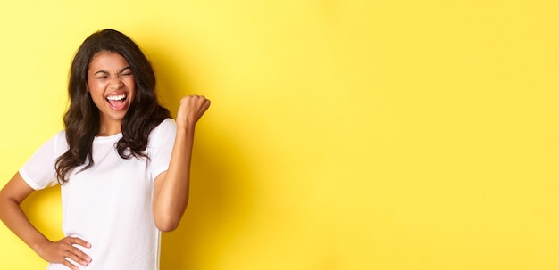 Free photo portrait of happy africanamerican woman triumphing and winning making fist pump and shouting for joy