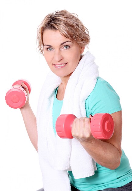 Portrait of happy aged sportswoman with dumbbells
