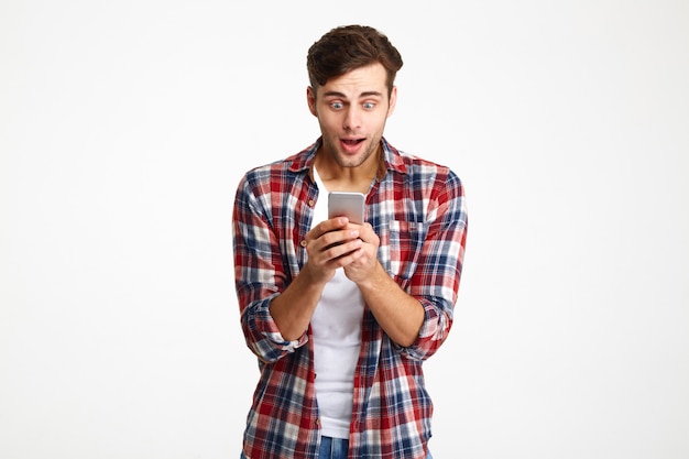 Portrait of a happy amused man looking at mobile phone