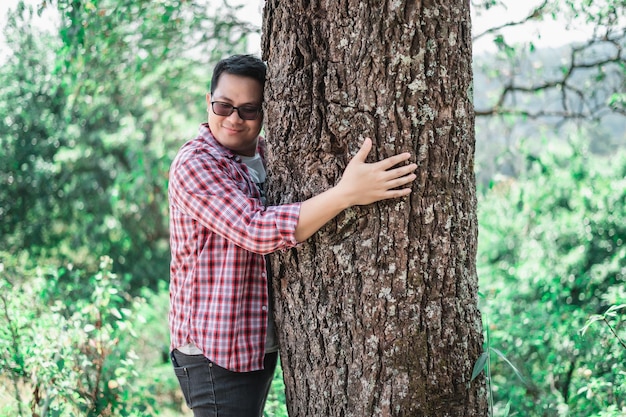 Portrait of Happy Asian man hugging a tree in forest Protecting and love nature Environment and ecology concept