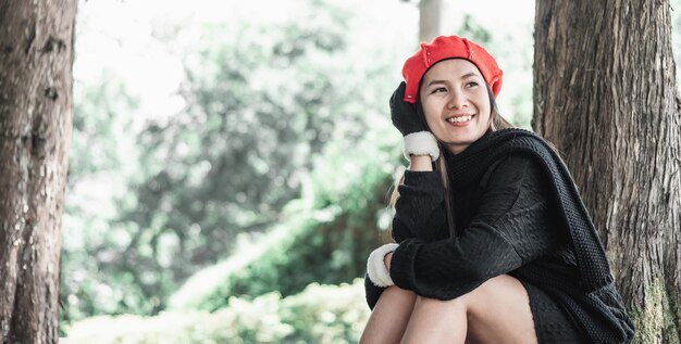 Portrait of Happy Asian young woman sitting on a lawn under a tree in park Concept of care for environment