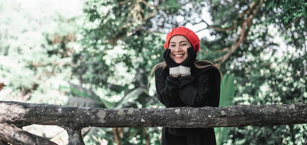 복사 공간 휴가 및 여행 개념이 있는 숲에서 겨울 의상을 입은 행복한 아시아 젊은 여성의 초상화
