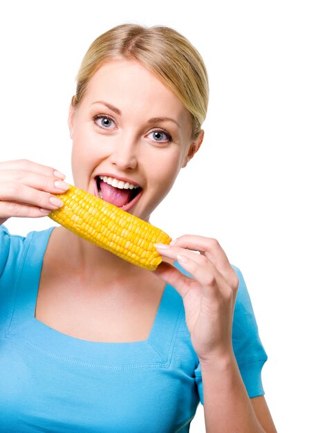 Портрет счастливой красивой девушки, кусающей сырую кукурузу
