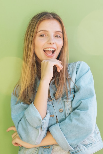 Portrait of a happy blonde young woman against mint green backdrop