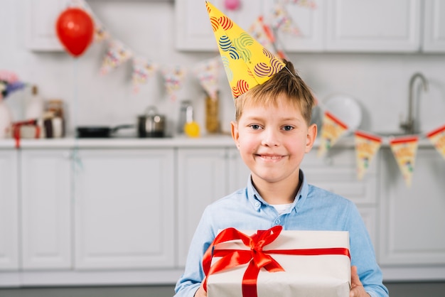Портрет счастливый мальчик держит подарок на день рождения на кухне