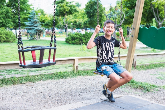 Portrait of happy boy sitting in the swing
