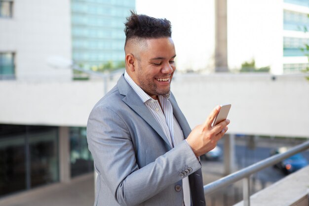Portrait of happy businessman reading message and laughing