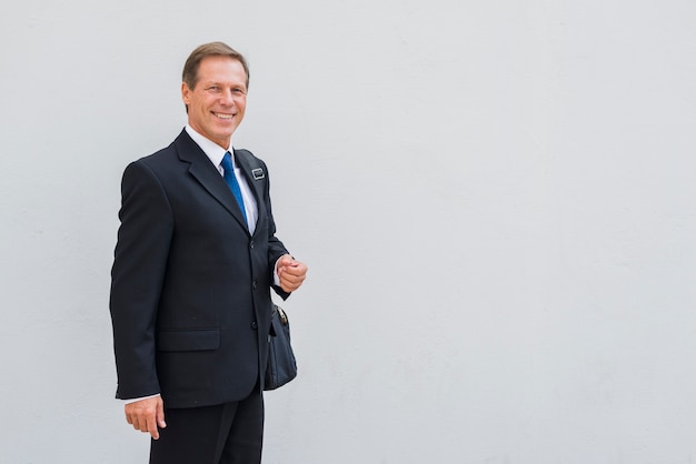 Free photo portrait of a happy businessman standing against grey backdrop