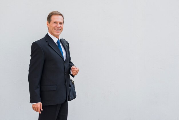 Portrait of a happy businessman standing against grey backdrop