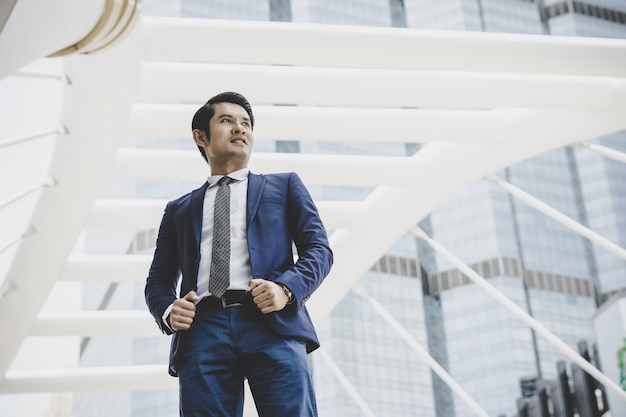 Free photo portrait of happy businessman standing on front of business center.