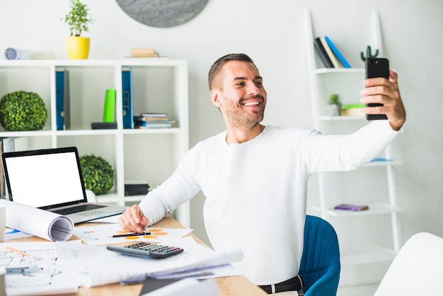 Portrait of a happy businessman taking selfie from mobile phone