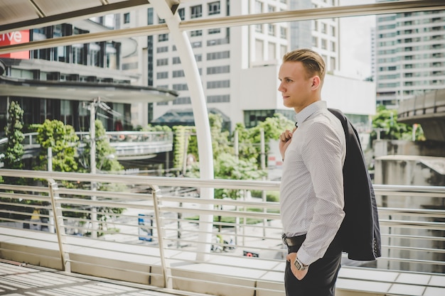 Portrait of happy businessman with hand holding suit, Finish work standing on the way to back home.