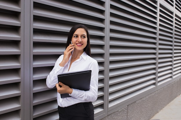 Portrait of happy businesswoman talking on mobile phone outdoors