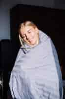 Free photo portrait of happy calm woman in bedroom in gray stripped blanket and black and beige body, home sleep wear