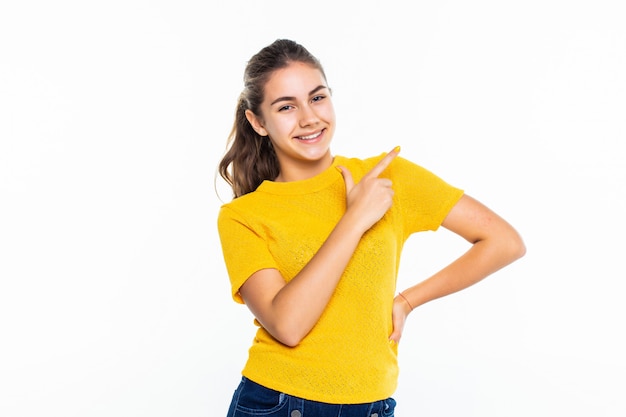 Portrait of a happy casual girl pointed up against white wall