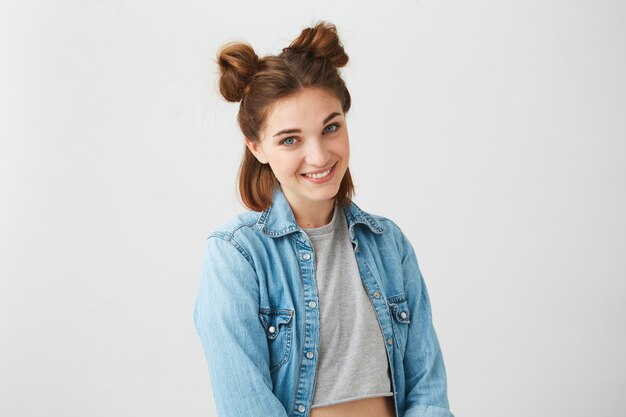 Portrait of happy cheerful beautiful girl with blue eyes and buns smiling .