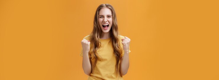 Бесплатный Фотография портрет счастливой веселой удачливой молодой европейской девушки с длинными натуральными волнистыми волосами, поднимающими сжатые волосы
