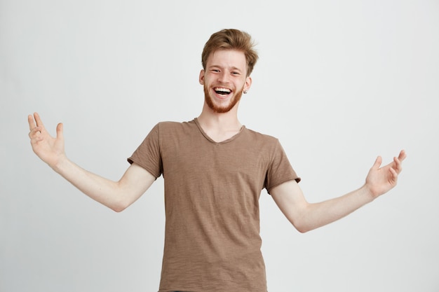 Portrait of happy cheerful positive young man laughing rejoicing gesturing looking at camera.