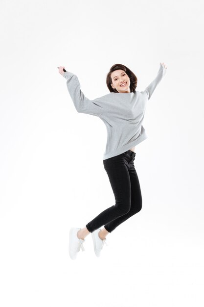 Портрет счастливой жизнерадостной женщины скача и празднуя успех