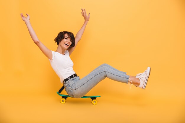 Портрет счастливой веселой женщины, сидя на скейтборде