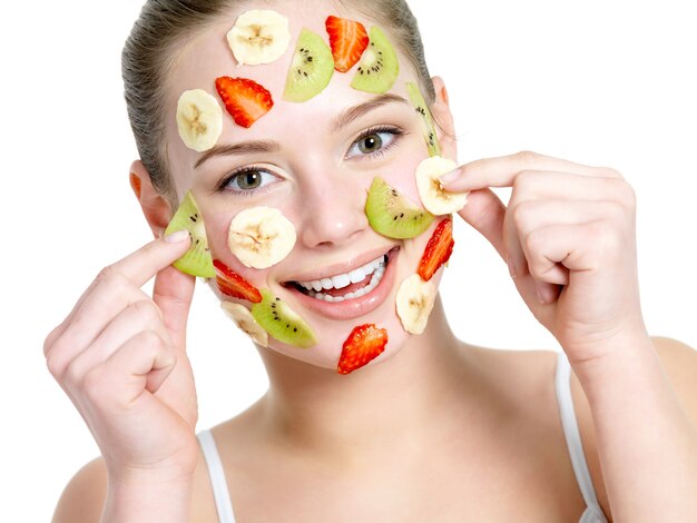 Portrait of happy cheerful young beautiful woman with fruit facial mask - isolated on white