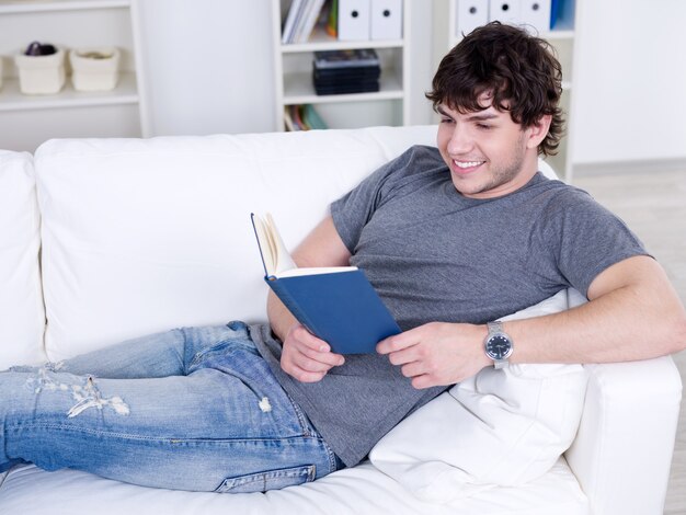 Portrait of happy cheerful young handsome man reading - at home