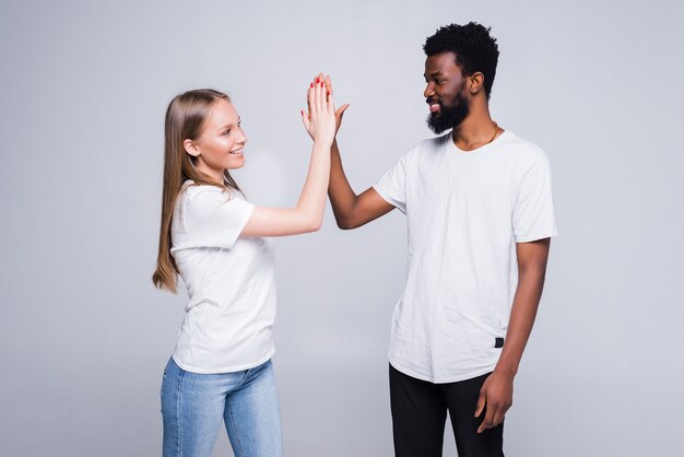 Portrait of a happy couple giving high five isolated over white wall