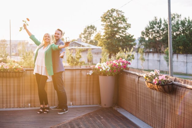 ワイングラス、バラ、バルコニーで抱き合っている幸せな夫婦の肖像