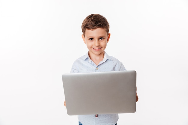 Portrait of a happy cute little kid holding laptop computer