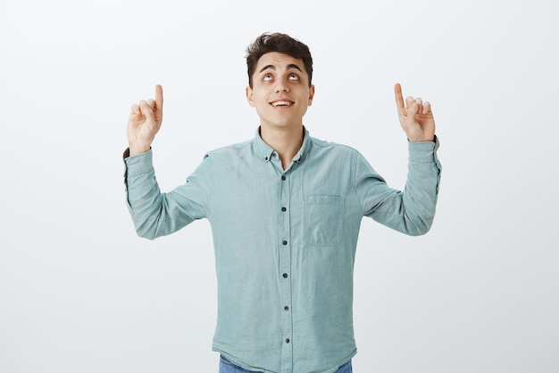 Free photo portrait of happy dreamy european man pointing up