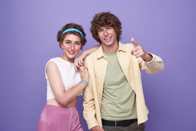 Portrait of happy excited couple tourists pointing hands to front