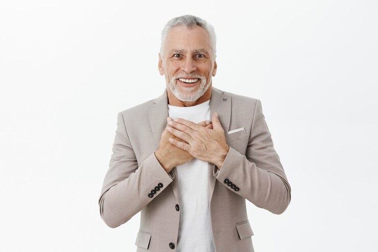 無料Photo お世辞と驚いて見える幸せな興奮した年配の男性の肖像画、胸に手をかざす