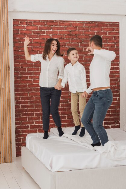 Portrait of happy family jumping in bed