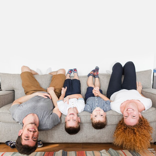 Portrait of a happy family lying upside down on sofa