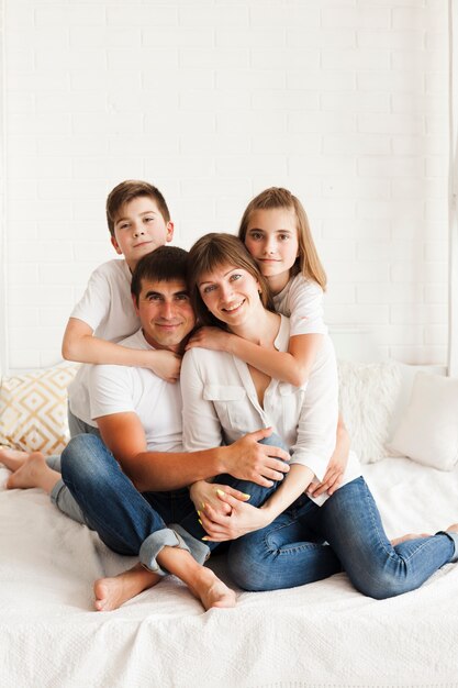 Portrait of happy family sitting on bed at home